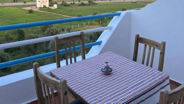 A balcony with a table and chairs, overlooking a mountainous landscape. - Olea Azul (chefchaouen)