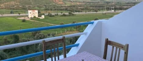 Un balcon avec une table et des chaises, donnant sur un paysage montagneux.