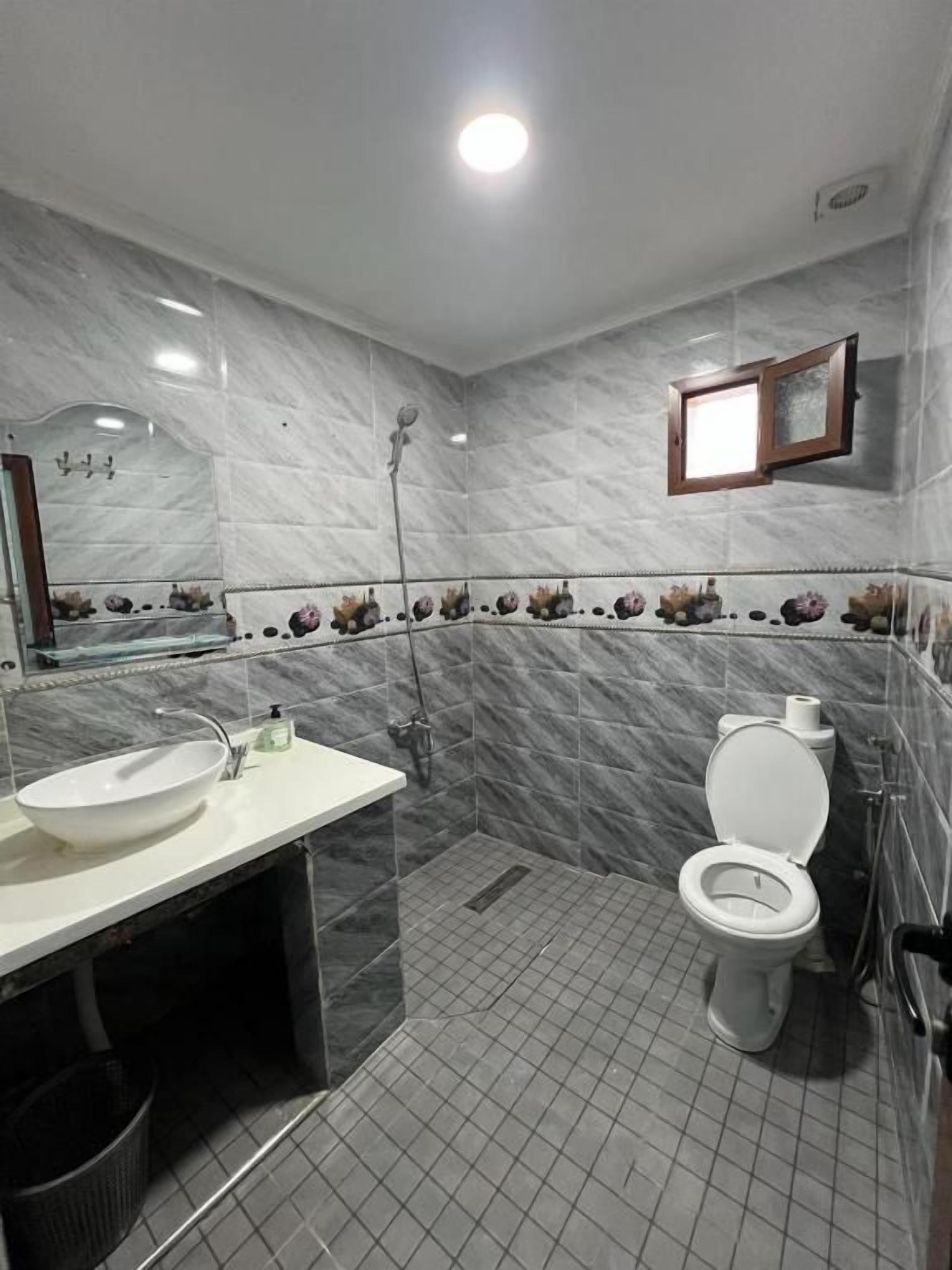 A bathroom with a white sink, toilet, and shower.