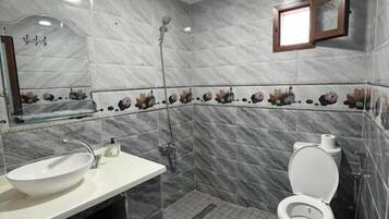A bathroom with a white sink, toilet, and shower.