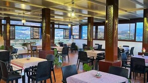 An indoor dining area with multiple tables and chairs, large windows, and a view of the landscape. - Olea Azul (chefchaouen)