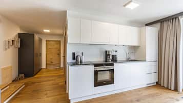 A modern kitchen with white cabinets, a built-in oven, and a coffee maker.