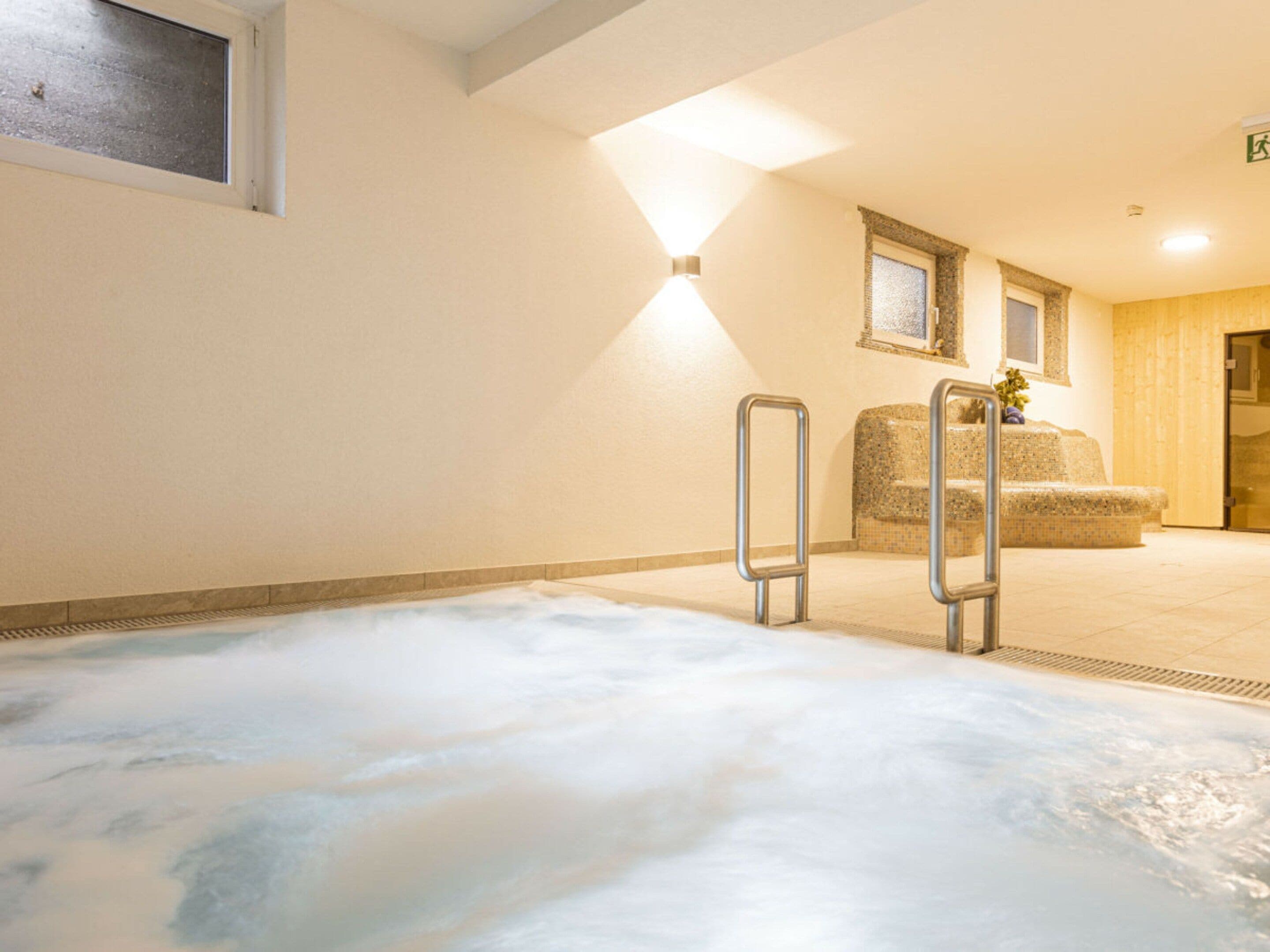 A spa area with a hot tub, a seating area with a cushioned bench, and a wall-mounted mirror.
