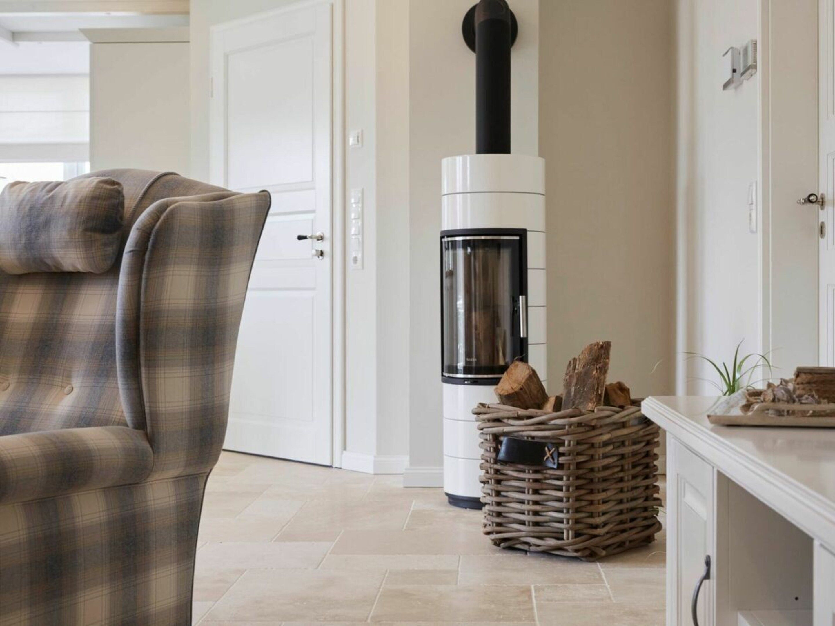 Una sala de estar con sofá, chimenea y una cesta de mimbre con leña.