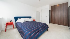 Een slaapkamer met een bed, een nachtkastje, een kledingkast en een deur.