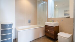 Een moderne badkamer met een douchecabine van glas, een witte wastafel en een toilet.