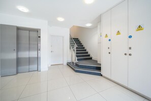 A clean, modern lobby with a staircase, an elevator, and fire safety signs. - Bright & Stylish 1-Bed Flat in Central Watford - Pass the Keys (St Albans)