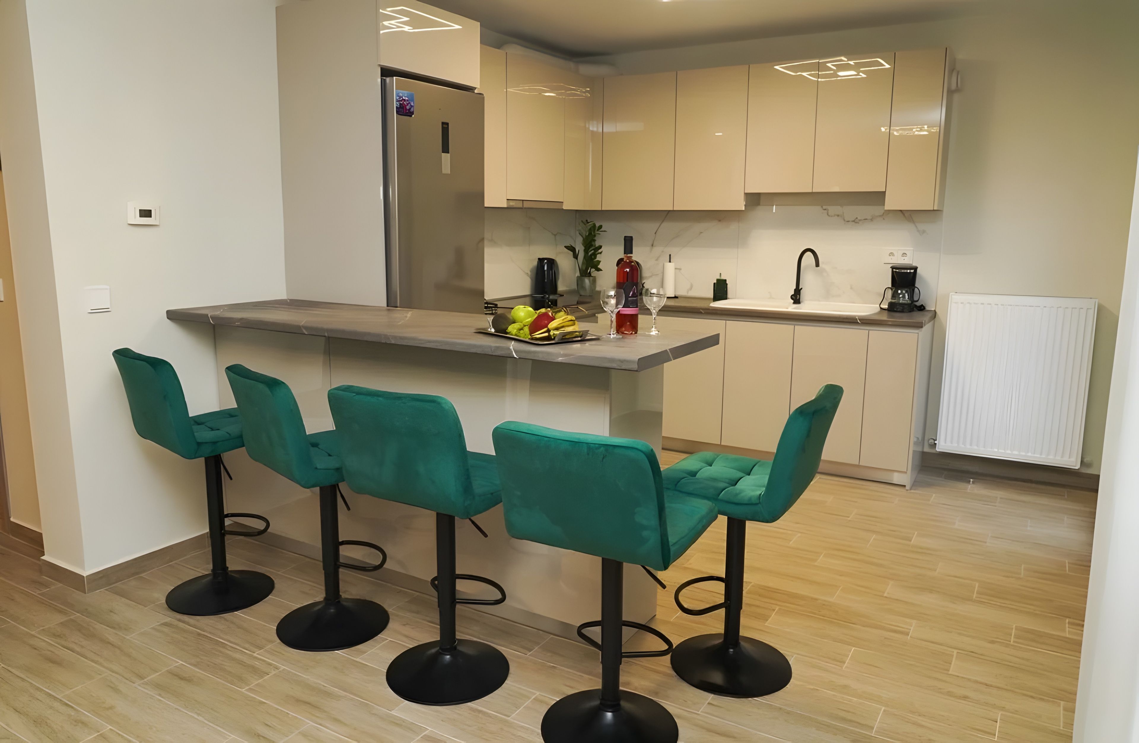 A modern kitchen with a central island, bar stools, and a coffee machine.
