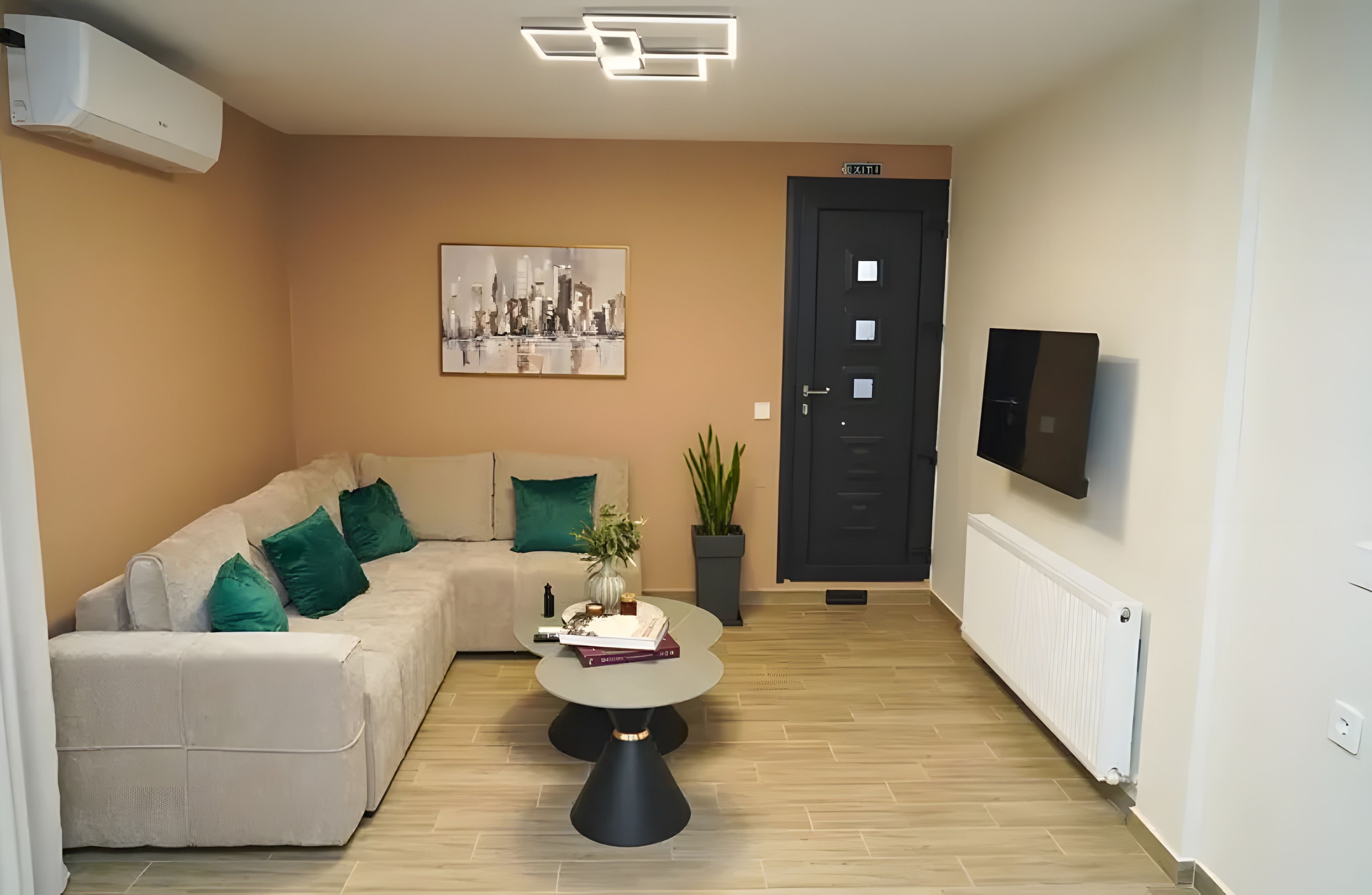 A modern living room with a sofa, a coffee table, a painting, a potted plant, and a door.
