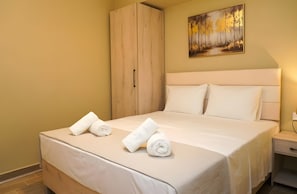 Une chambre d’hôtel avec un lit, une armoire, un tableau au mur et une table de chevet.
