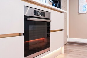 A modern kitchen with a built-in oven and a coffee machine on the countertop. - Modern Cosy Home w/ Stylish Interior - Pass the Keys (Borehamwood)