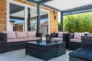 Ein Terrassenbereich im Freien mit Korbmöbeln und einem Glastisch.