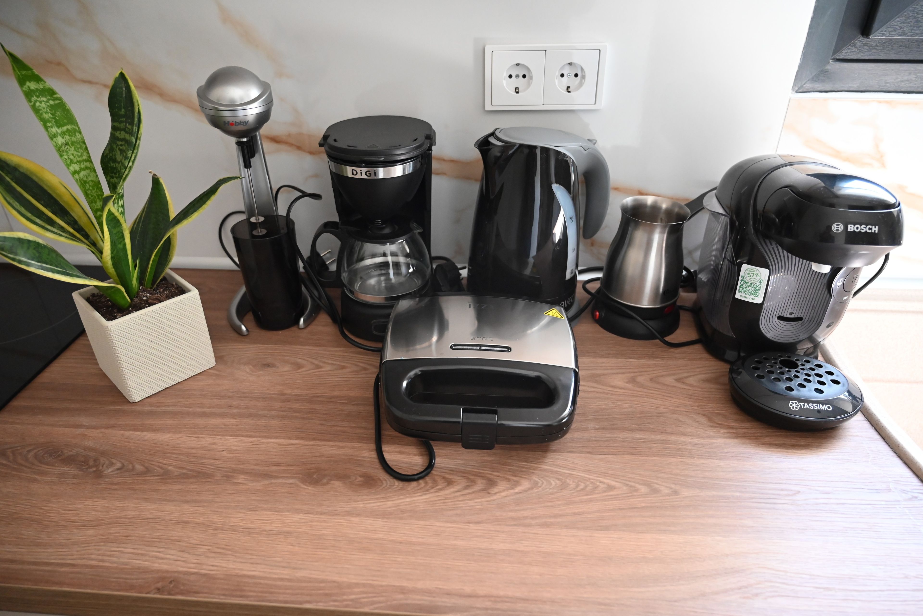 Un plan de travail de cuisine équipé de divers appareils, notamment une machine à café, une bouilloire et un grille-pain.
