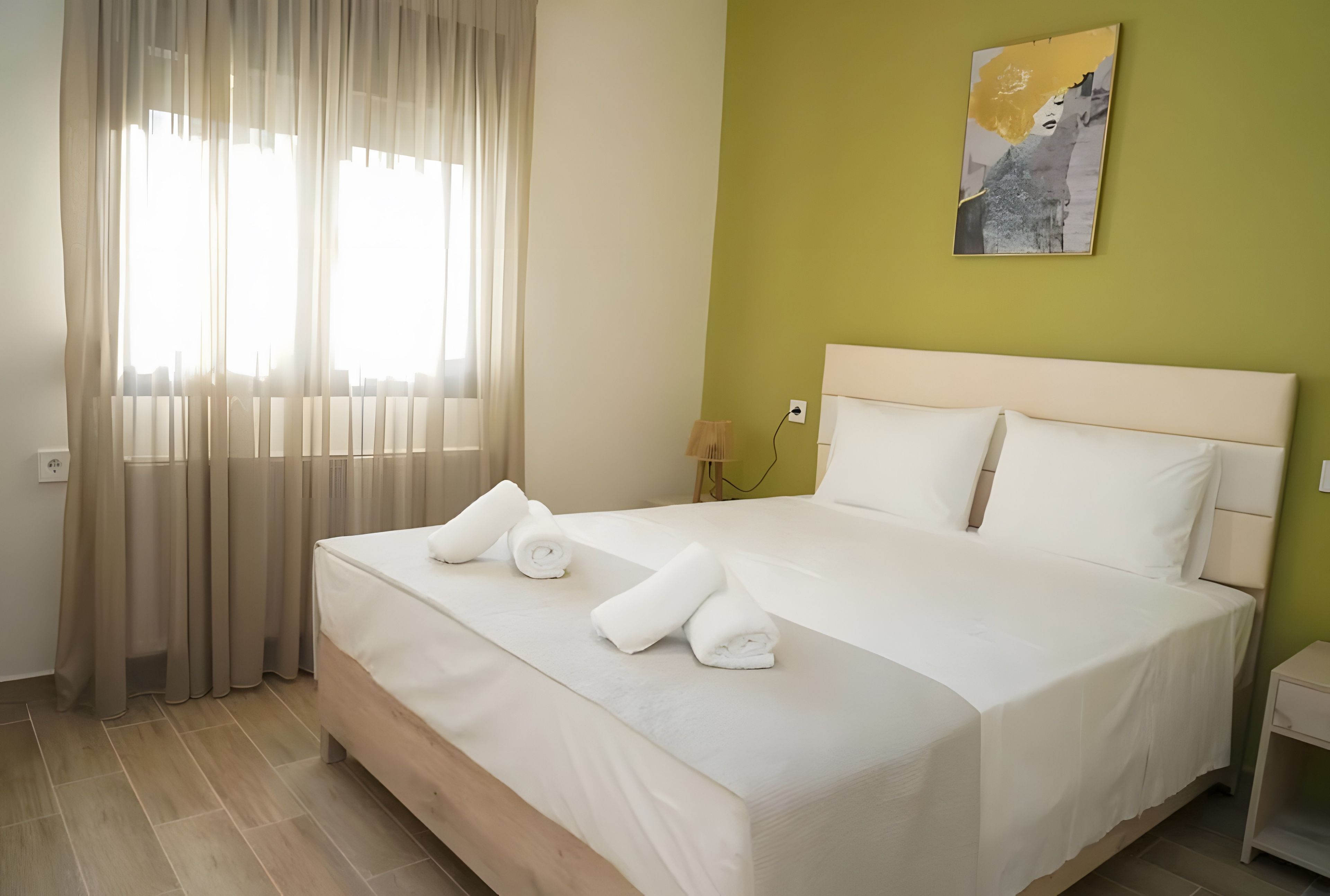 Una habitació d'hotel amb un llit, cortines, un quadre a la paret i una taula de nit.