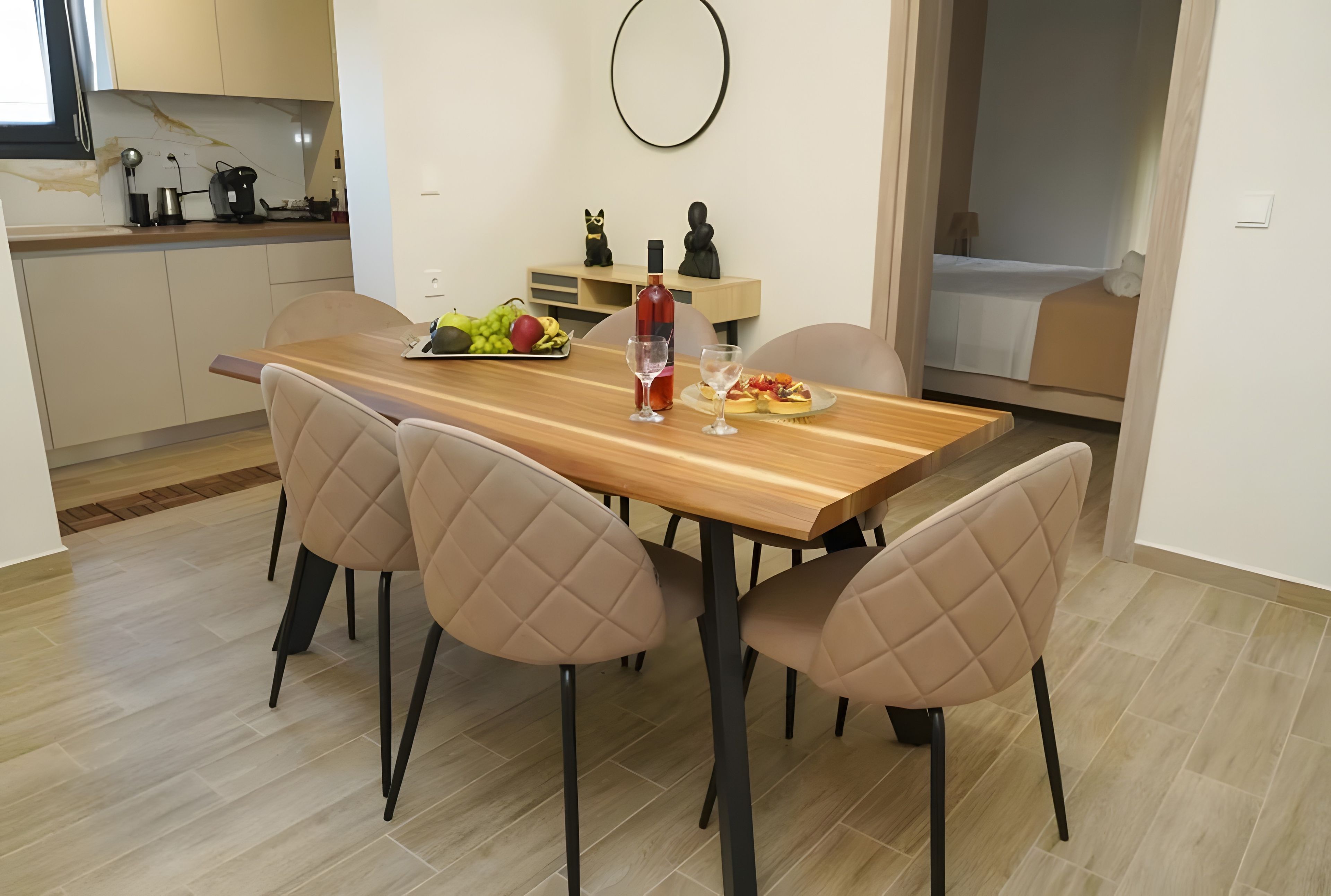 Un comedor moderno con una mesa de madera, sillas acolchadas y una bandeja de frutas.