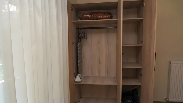 Un armario espacioso con estantes de madera, una barra para colgar ropa y un radiador.
