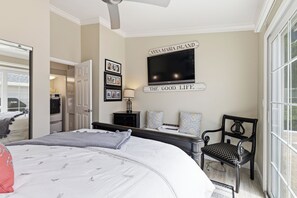 A bedroom with a bed, a TV, a chair, and a wall with a sign. - Exquisite Perico Bay Club 2 BR Condo-AMI Beaches, Sunsets, Nature,Fishing, Pool (Bradenton)