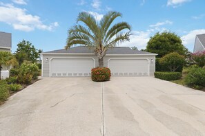 A residential garage with a palm tree and a flower bush in front. - Exquisite Perico Bay Club 2 BR Condo-AMI Beaches, Sunsets, Nature,Fishing, Pool (Bradenton)