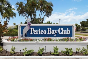 Une enseigne pour le Perico Bay Club, avec la silhouette d’une personne et des palmiers en arrière-plan.