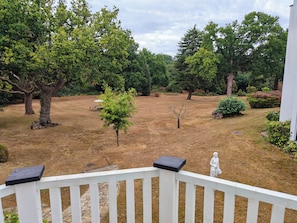 A residential outdoor area with a lawn, trees, a white fence, and a statue.