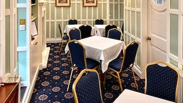A dining room with a patterned carpet, white walls, and blue chairs.