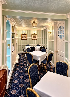 A dining room with a patterned carpet, white walls, and blue chairs.