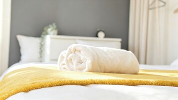 Una cama bien hecha con una toalla blanca y un edredón amarillo.