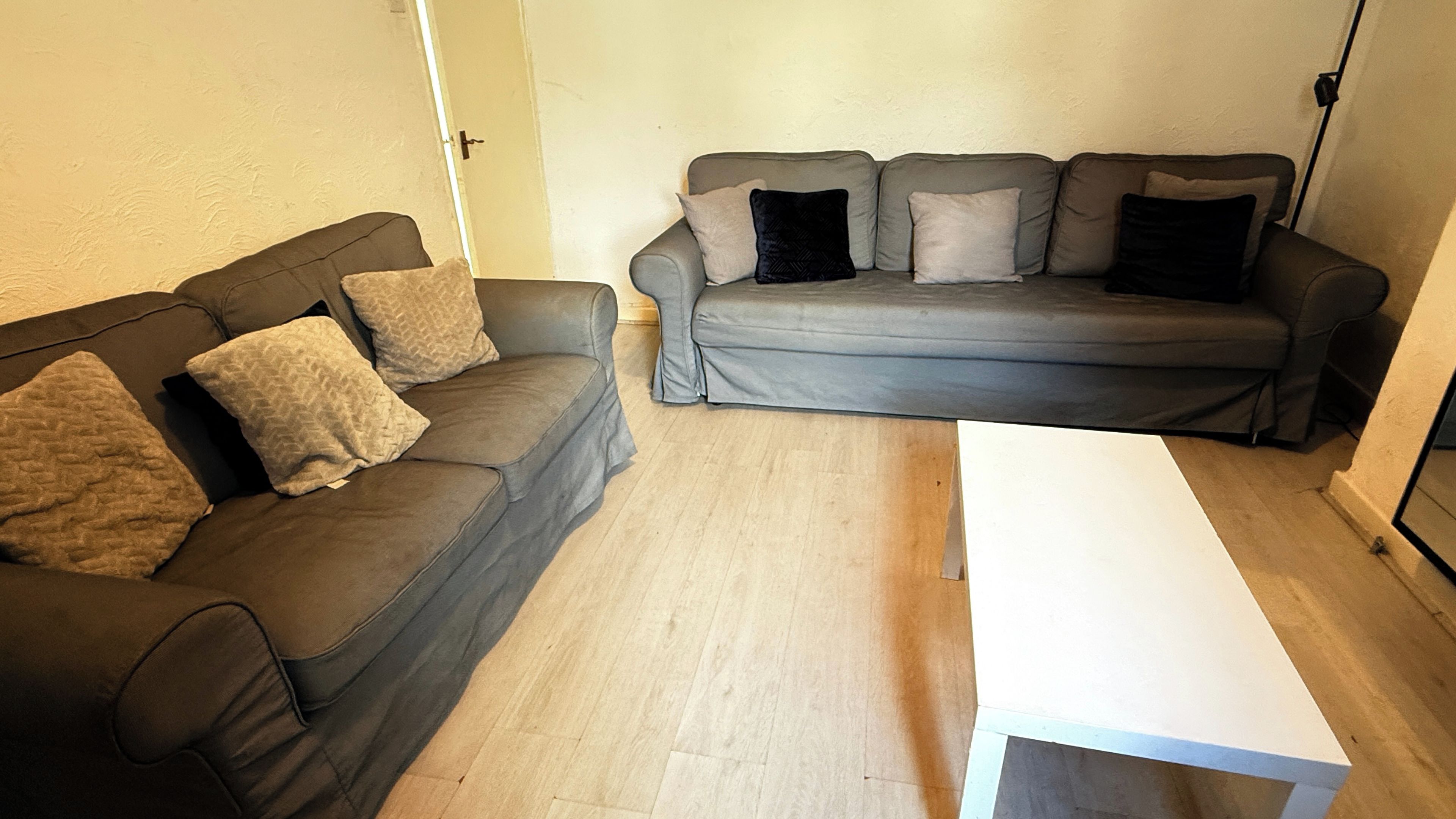 A living room with two sofas, a coffee table, and a door.