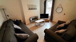 Una sala de estar con dos sofás, una mesa de centro, un televisor y una chimenea.