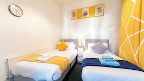 A hotel room with two beds, a clock, and three framed pictures on the wall. - Seaside Serenity Retreat in Wallasey (Wallasey)