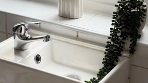 A bathroom with a white sink, chrome faucet, and a small potted plant on the windowsill. - House Sleeps 7 With Parking (Wallasey)