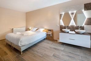 Ein modernes Schlafzimmer mit einem großen Bett, Nachttischen, einem Schminktisch mit Spiegel und Holzboden.