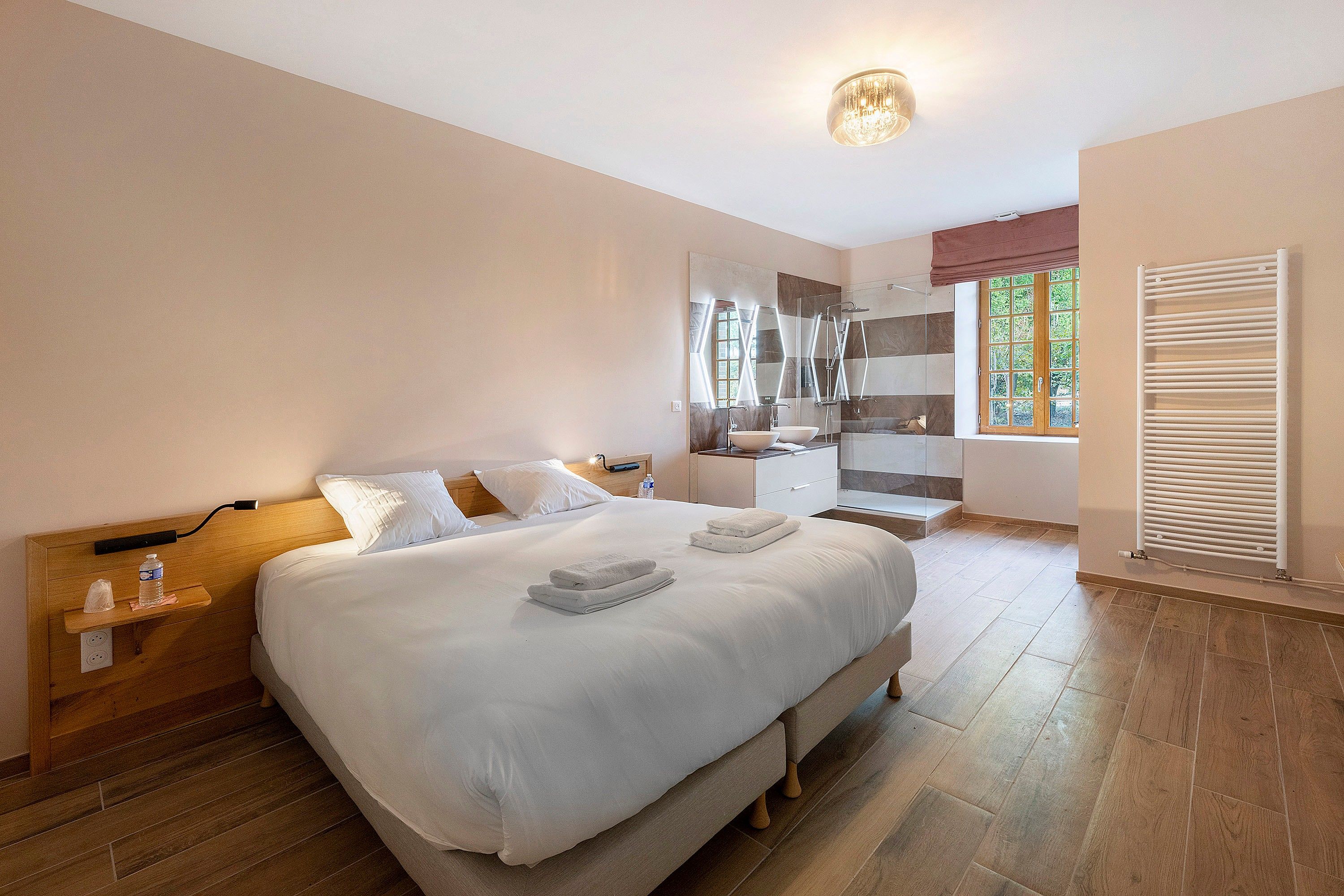 Une chambre d’hôtel avec un grand lit, une salle de bain avec douche et une fenêtre équipée de stores.