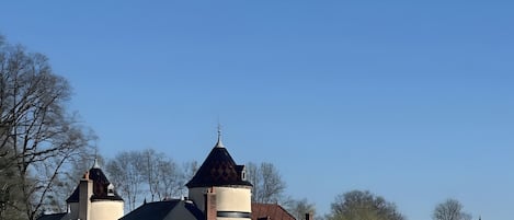 Un grand bâtiment doté d’une tour imposante et de fenêtres en arc de cercle, entouré d’une pelouse bien entretenue.