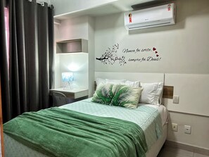 A hotel room with a bed, a desk with a lamp, an air conditioning unit, and a decorative wall with a tree branch and hearts. - 2802 Unique · Studio Unique with garage (Sacramenta)