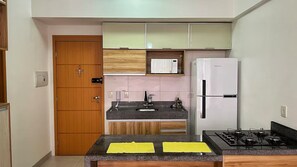A compact kitchen with a built-in oven, a refrigerator, and a gas stove. - 2802 Unique · Studio Unique with garage (Sacramenta)