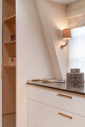 Interior moderno com teto inclinado, prateleira embutida com objetos decorativos e luminária fixada na parede.