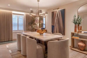 A modern dining area with a large table, cushioned chairs, and a chandelier. - Cadogan Street IV by onefinestay (London)