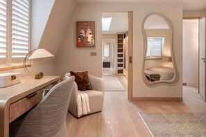 A bedroom with a desk, a chair, a bed, a mirror, and a painting on the wall. - Cadogan Street IV by onefinestay (London)
