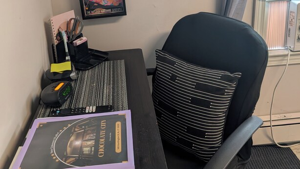 A desk with a notebook, a clock, and a framed picture on the wall. - 146-6 Dizzy Gillespe Upper-Level Retreat 2Gather Self		1 Bedroom Studio. (New London)