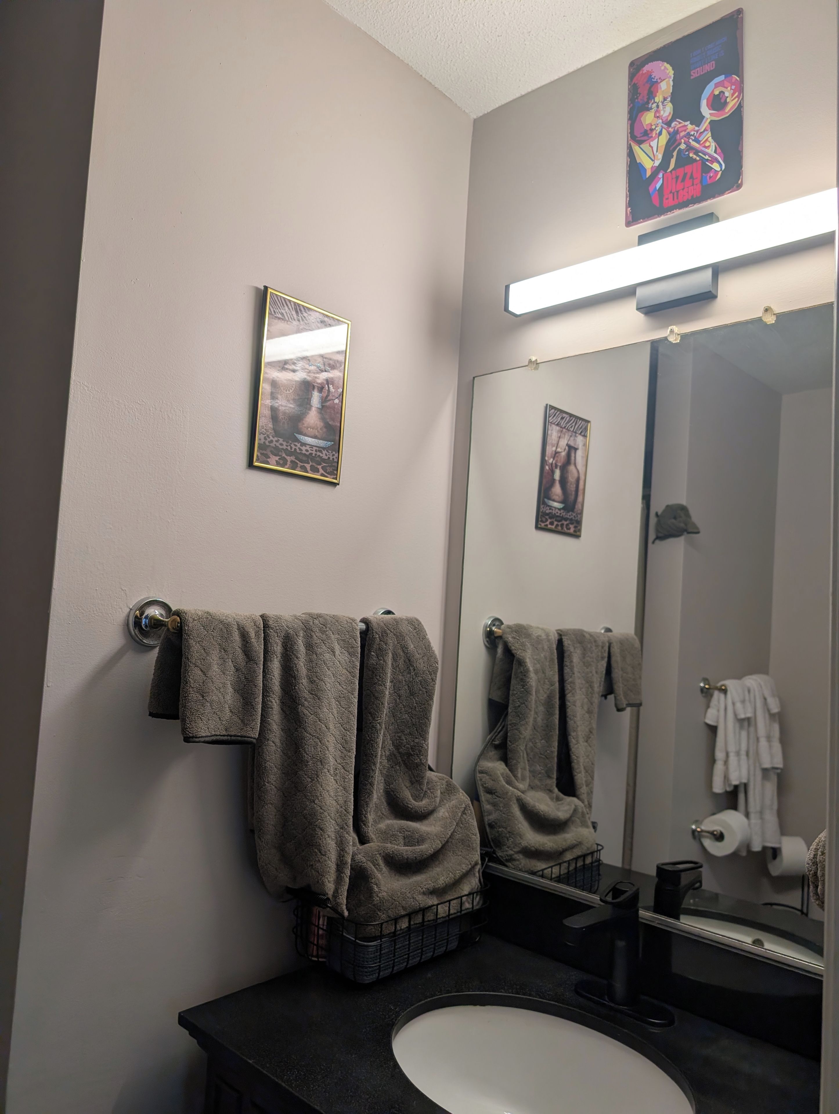 A bathroom with a mirror, two towels, a sink, and a toilet.