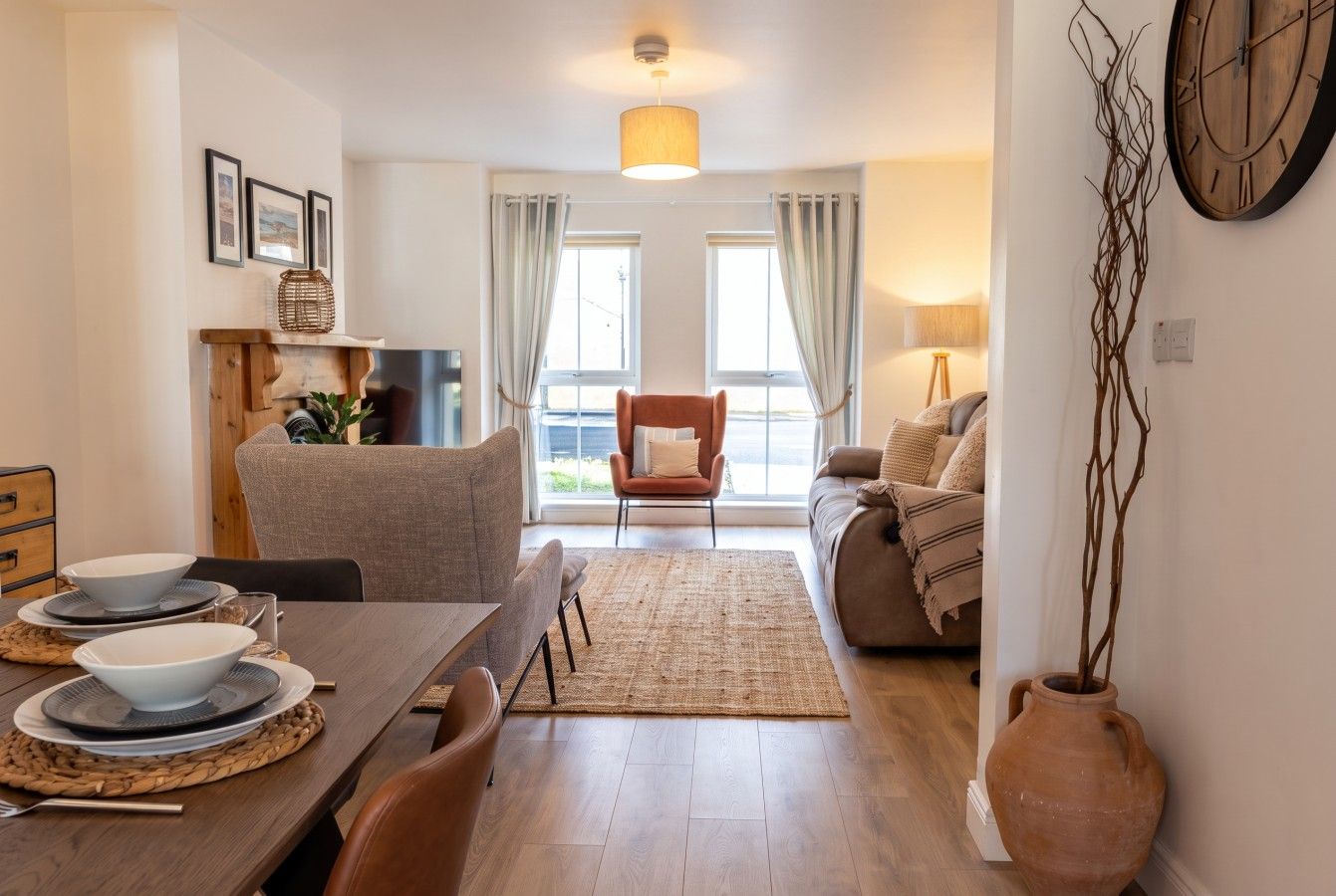 Een moderne woonkamer met een eethoek, een bank, een salontafel en een open haard.