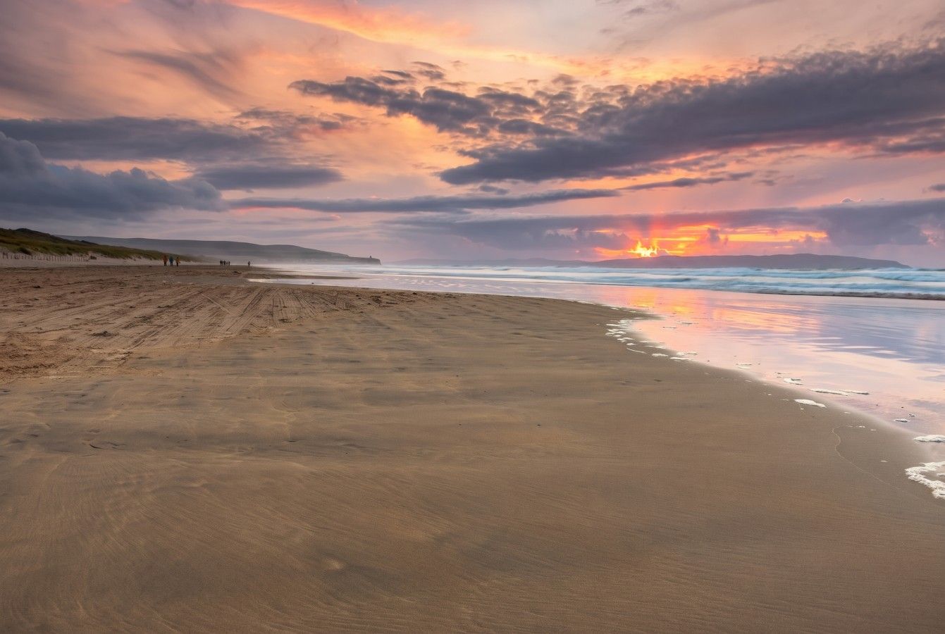 Una platja amb un capvespre, mar tranquil·la i cel serè.