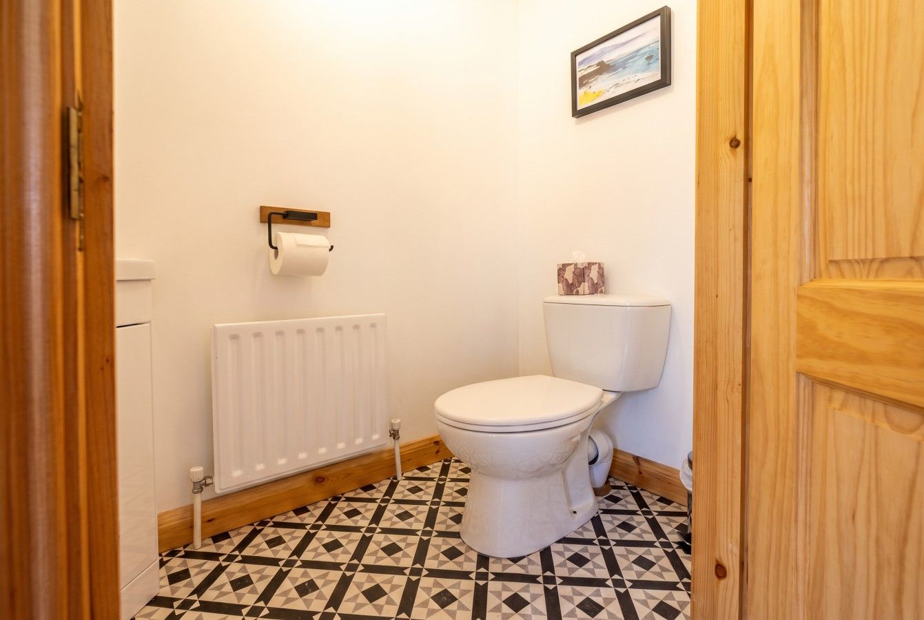 A bathroom with a toilet, a radiator, and a patterned floor.