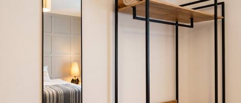 A bunk bed with a wooden platform and a metal frame, a mirror with a wooden frame, and a lamp on a bedside table.