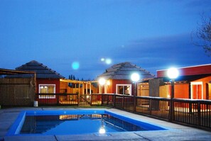 Una piscina con área cercada, rodeada de edificios con fachadas rojas y anaranjadas.
