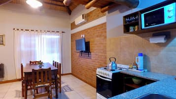 Una cocina compacta con estufa a gas, microondas y televisor montado en la pared.