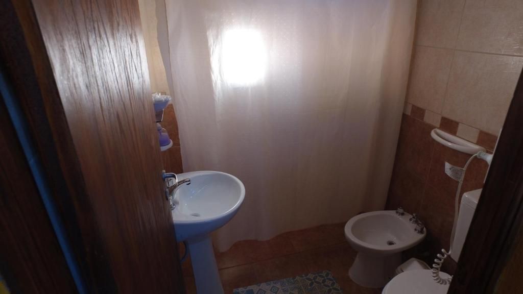 A small bathroom with a sink, bidet, and toilet.