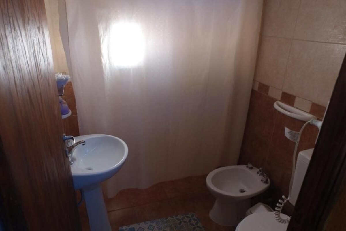A small bathroom with a sink, bidet, and toilet.