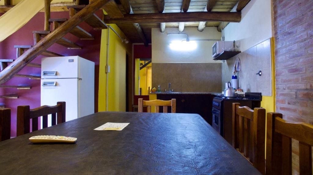 Una cocina con una mesa de madera, sillas y un refrigerador.